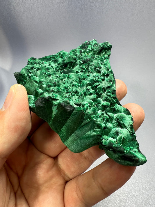 a hand holding a piece of green rock